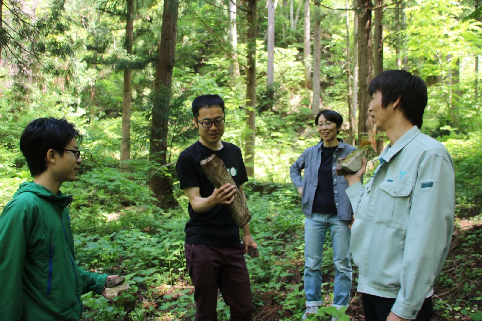 飛騨の森で石を手に語り合うメンバー