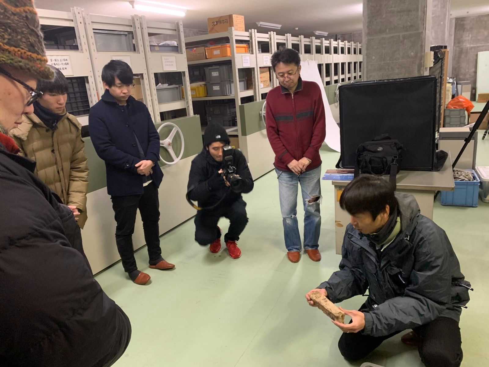 収蔵庫で石棒を手に取って解説するバックヤードツアー